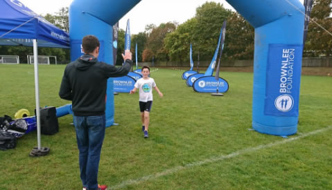 boys runs to finish line at Park Club triathlon